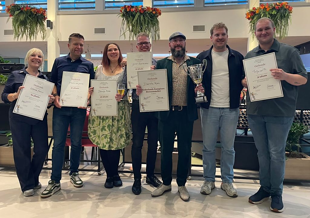 The Dutch team for the World Cup in 2027 holding up their certificates of the Dutch Cup of Beer Sommeliers stating their place in the finale and the Dutch Champion of 2024 and World Champion of 2025 Léon Rodenburg who was the judge this year inbetween.
From left to right: Elianne, blonde hair, wide smile, blue clothes, Martin, short hair, wide smile, blue clothes, me, brown hair, wide smile, with pullover, selfmade green skirt with a hopplant print, Yoran, short blonde hair, wide smile, blue shirt, black trousers, Dennis, blue hat, salt-and-pepper beard, green suit, Léon, blonde curly hair, blue jacket, white shirt, jeans, Thijs, short hair, wide smile, sage shirt, jeans.